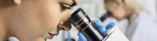 Kvindelig studerende kigger i mikroskop