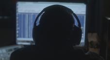 Person with headphones looking at computer screen in a dark room
