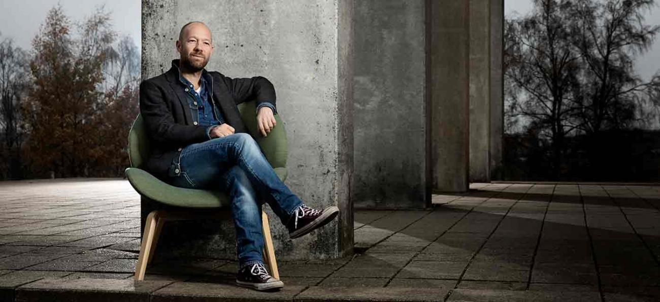 Lektor Jacob Rasmussen sidder udendørs på Roskilde Universitet 