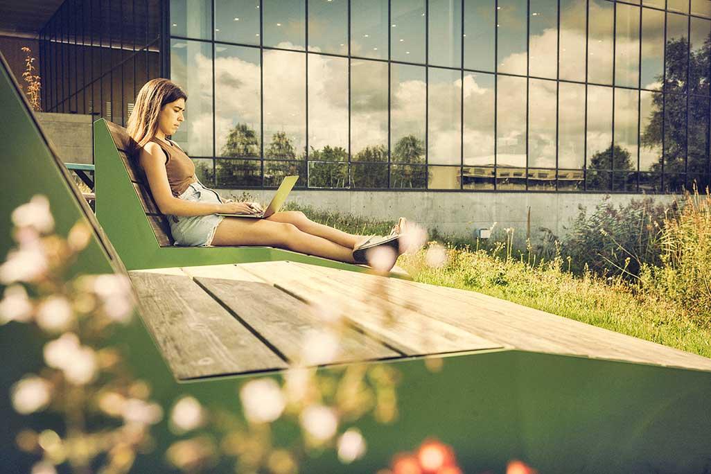 Kvindelig studerende sidder udenfor og arbejder