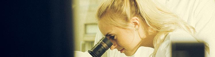 Kvindelig studerende kigger i mikroskop